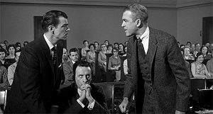 브룩스 웨스트(왼쪽)와 제임스 스튜어트(오른쪽)가 마주보고 있고, 조지 C. 스콧(가운데)이 지켜보고 있다