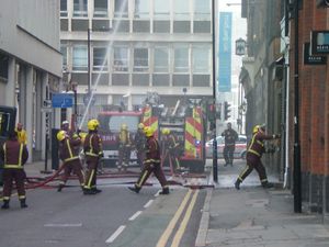 LFB 소방관들이 건물 화재 현장에서 도끼(오른쪽)를 사용하여 진입하고 있다