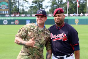 2016년 7월 3일 일요일, 노스캐롤라이나 포트 브래그에서 열린 마이애미 말린스와 브레이브스의 정규 시즌 경기 시작 전, 알렉스 버넷 일등 상사와 애틀랜타 브레이브스 투수 아로디스 비즈카이노가 머리 장비를 교환하는 모습.