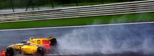 A black, yellow and red Formula One car racing at speed on a wet track