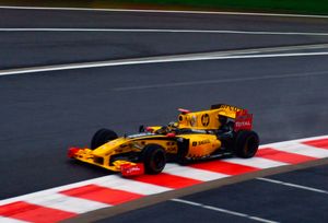 A yellow and black Formula One vehicle being driven uphill on a race circuit