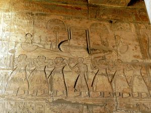 Relief showing rows of men carrying poles that support a model boat