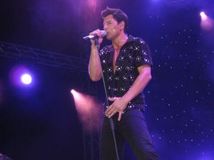 어두운 옷을 입고 마이크에 대고 노래하는 젊은 남자