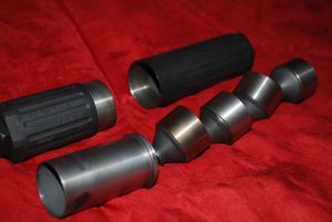 총기 소음기를 분해하여 (아래에서 시계 반대 방향으로) 폭발 챔버, 배플 및 외부 튜브 섹션을 보여준다.