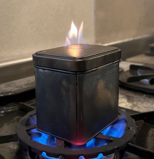 오래된 수건을 뚜껑에 구멍을 낸 홍차 캔에 채워 가열하여 숯 천을 만드는 모습. 발생한 가스가 연소되고 있다. 가스가 나오지 않을 때까지 가열한다.