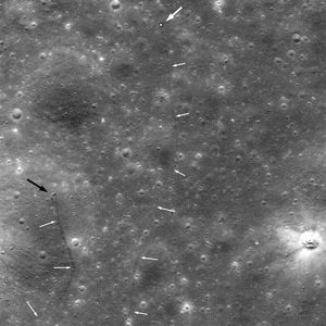 달 궤도선(Lunar Reconnaissance Orbiter)이 촬영한 루노호트 2호와 궤적. 큰 흰색 화살표는 로버를, 작은 흰색 화살표는 로버의 궤적을, 검은색 화살표는 치명적인 달 먼지를 뒤집어쓴 분화구를 나타냅니다.