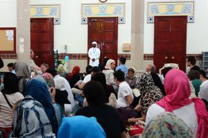 방문객들이 가이드 앞에서 주메이라 모스크에 앉아 있다.