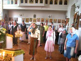 정교회의 성체성사 중의 광경. 중앙의 여성이 오른손을 정해진 형태로 정돈하여 이마에 대고, 정교회식으로 십자 표시를 하고 있다. 다른 십자 표시를 하고 있는 순간에 촬영되었기 때문에 오른팔이 흔들려 보이는 신도도 있다. (뒤셀도르프의 성모 호교 교회)