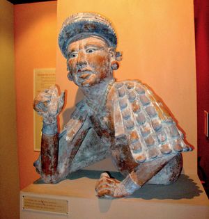 마야인이 갈아놓은 코코아 페이스트 막대기를 들고 있다.