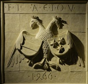 합스부르크 가문의 모토 F.I. A.E.I.O.U.가 새겨진 1466년의 문장. 왼쪽 부분은 합스부르크 가문의 문장이고 오른쪽 부분은 첼레 백작의 문장으로, 황제의 쌍두 독수리 아래 통합되었다.