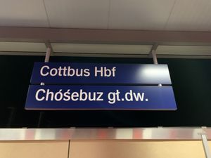 코트부스 중앙역의 이중 언어 표지판 - 독일어: Cottbus Hauptbahnhof (Hbf), 하부 소르브어: Chóśebuz głowne dwórnišćo (gł.dw.)