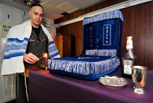 하누카 첫날을 기념하여 메노라에 불을 켜는 미 해군 군인