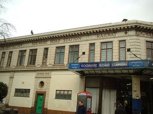 베이지색 건물로, 갈색 프레임 창문과 갈색 글씨로 "METROPOLITAN EDGWARE ROAD STATION RAILWAY"라고 적힌 표지판이 있다