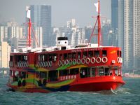스타 페리가 승객을 빅토리아 항구로 수송하고 있다. 이 특별한 페리는 홍콩을 아시아의 세계 도시로 홍보하는 광고로 칠해져 있다.