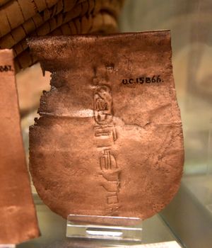 구리판, 도끼날의 일부일 가능성이 높으며, 하트셉수트의 카르투슈가 표시되어 있다. 매트로 덮인 작은 구덩이의 기초 퇴적물, 데이르 엘-바하리, 이집트. 이집트 제18왕조. 런던의 페트리 이집트 고고학 박물관