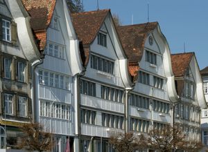 마을 광장(도르프플라츠)을 따라 구부러진 박공기를 보여주는 목조 주택