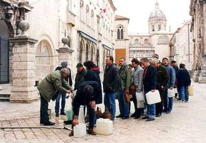 포위전 중 사람들이 수도관 앞에서 물을 받으러 기다리는 모습