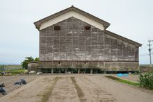 솟아오름의 예: 주변의 논밭이 침하하는 한편, 창고의 기초 말뚝은 침하하지 않고 노출되어 있다(사가현 시로이시정)