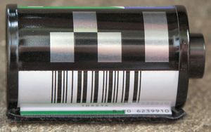 DX 인코딩을 사용한 필름 카세트. 은색과 검은색 전도성 DX 카메라 자동 감지 패턴 아래에 DX 번호를 포함하는 6자리 바코드가 있다.