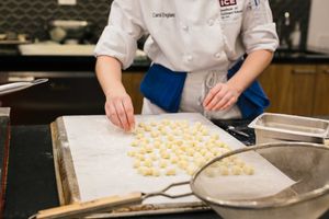 요리사가 양피지를 덮은 금속 베이킹 시트에서 음식을 준비하고 있다.