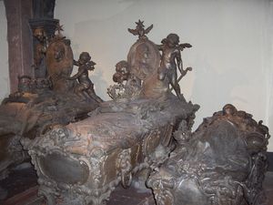 세 개의 회색 장식 석관이 나란히 서 있고, 가운데 석관 아래에 네 번째 석관이 있다