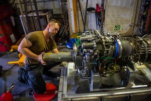미 해군 수병이 MH-60R 시 호크의 T700 엔진에 대한 정비를 수행하고 있다.