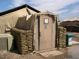 미 육군 텐트. 나무로 만들어진 입구, 에어컨, 방호를 위한 모래주머니가 설치되어 있다. 이라크 바그다드 승리 기지 (2004년 4월).