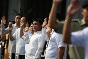 정부 공무원과 관리들이 필리핀 국기에 대한 충성 서약을 위해 오른손을 올리고 있다