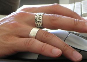 현대 은반지를 착용한 남자의 손, 하나는 부족 문양을 가지고 있다.