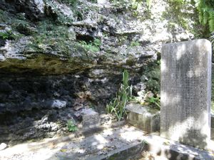 A memorial slab in a lush environment near a rockycliff overhang