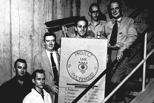 “Project Poltergeist” 팀의 중성미자 탐색 단체 사진; 프레데릭 레인스(Frederick Reines)가 포스터를 들고 있고, 클라이드 코완(Clyde Cowan)은 맨 오른쪽에 있다; 로스앨러모스 과학 연구소, 1953년경