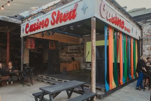 Casino Shed라고 적힌 빈티지 스타일의 빨간색 텍스트와 다채로운 스트리머로 둘러싸인 무대의 사진