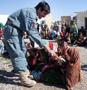 헬만드에서 새로운 여자 학교 개교식에서 아프간 경찰관이 여학생에게 책을 주고 있다