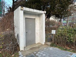 벙커 문, 놀이터 옆에 위치해 있다. 문에는 표식이 없으며, 오른쪽에 있는 표지판은 이곳을 단지 "보존 구역"으로 묘사하고, 부모들에게 아이들을 이곳에 가까이 가지 못하도록 경고한다. (2023)