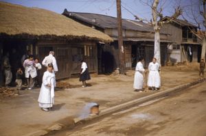 백색 의복을 착용한 한국의 노인들이 한국 전쟁 종전 직후 버스를 기다리고 있다. 사진 속 다른 사람들은 색깔 있는 옷을 입고 있다. (1953)
