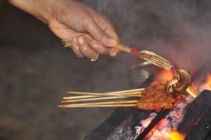 사테에 소스를 바르는 모습, 말레이시아, 보르네오, 사바의 딴중아루 해변 노점 음식점에서.