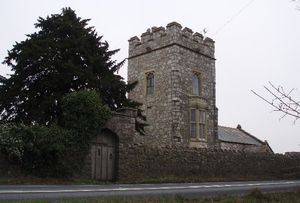 돌담 뒤의 사각 석조 탑과 나무에 가려져 있음.