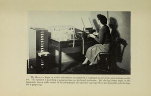 EDSAC 컴퓨터용 서브루틴 라이브러리가 펀칭 테이프 릴에 담겨 있는 보관 캐비닛 옆에서 작업하는 여성