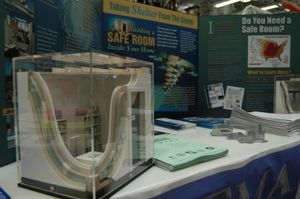 FEMA 완화는 미국 고풍 지역 주택 내 안전실 구축에 대한 정보를 제공합니다. 안전실 모형이 전경에 나와 있습니다.