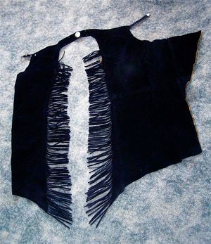 승마 쇼용으로 디자인된 스웨이드 샷건 챕스 한 쌍. 왼쪽 다리는 착용 시와 같이 닫혀 있고, 오른쪽 다리는 구조를 보여주기 위해 펼쳐져 있다.