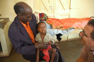 잠비아의 한 마을 주민이 필립 투마 박사 덕분에 목숨을 건진 손자를 안고 있다. 뇌성 말라리아로 죽을 뻔했지만 영구적인 시각 장애를 갖게 되었다.