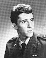 고개를 왼쪽으로 돌린 남자가 약간 미소를 지으며 사진을 찍고 있다.