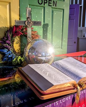 A church altar decorated with a disco ball and colors celebrating LGBTQ pride.