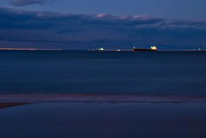 화물선이 밤에 다리-터널 단지를 건너기 위해 줄지어 서 있다