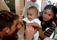 필리핀에서 아기를 검사하는 제1특수부대 그룹 대원