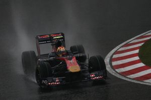 A navy-and-gold single-seater racing car is driven around a drenched tarmac course.