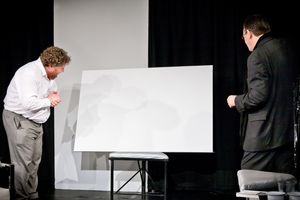 세르주와 마르크가 영국 세인트앨번스의 OVO 극단에서 2011년에 제작한 연극에서 흰색 그림을 감상하고 있다.