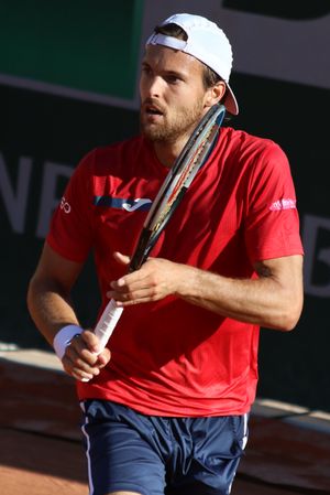 흰색 셔츠와 모자를 쓴 주앙 소자 선수가 서브를 넣기 전 아래를 보고 있다