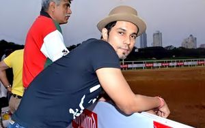 Hooda leaning on the fence of an Equestrian ground.