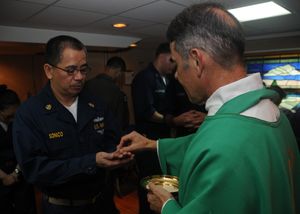 해군 사제가 미 해군 함선에서 가톨릭 신자에게 영성체를 주고 있다.